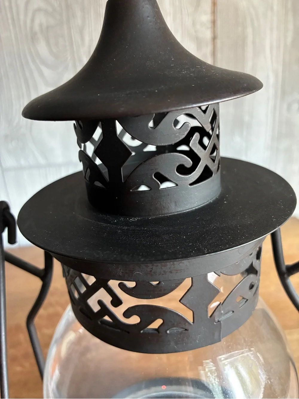 Decorative black metal hurricane lantern/candle lantern. It has a clear glass